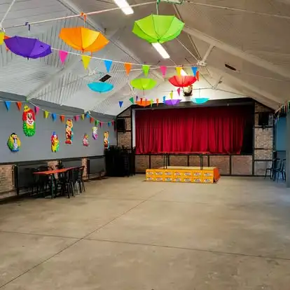 La salle des fêtes décorée de parapluies colorés, avec sa scène au rideau rouge