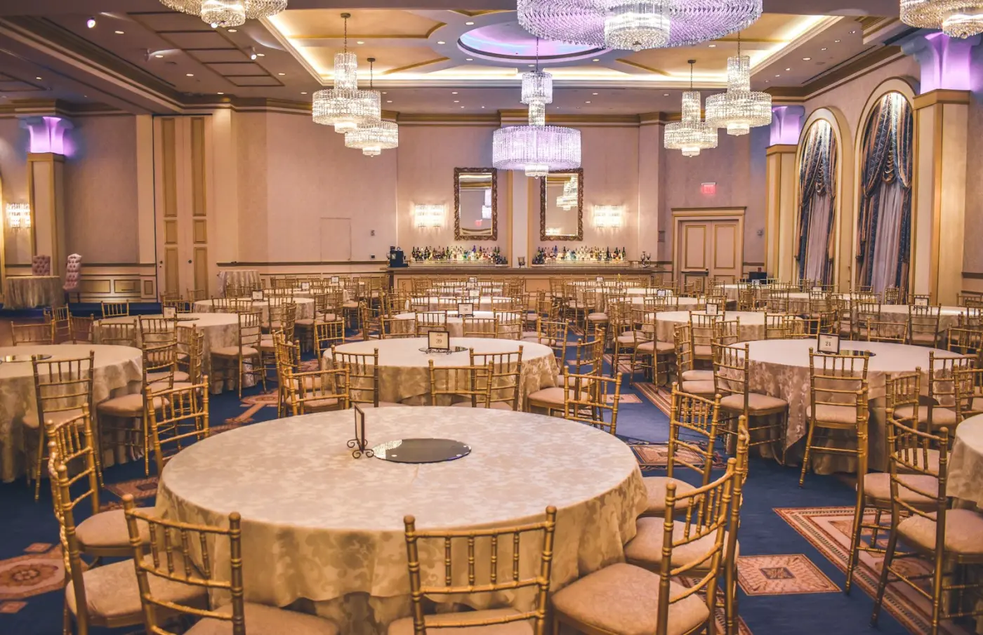 Tables rondes, chaises dorées et lustres dressés pour une réception